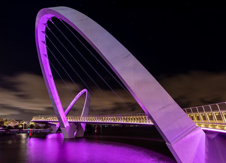 Arched footbridge with violet lighting at night