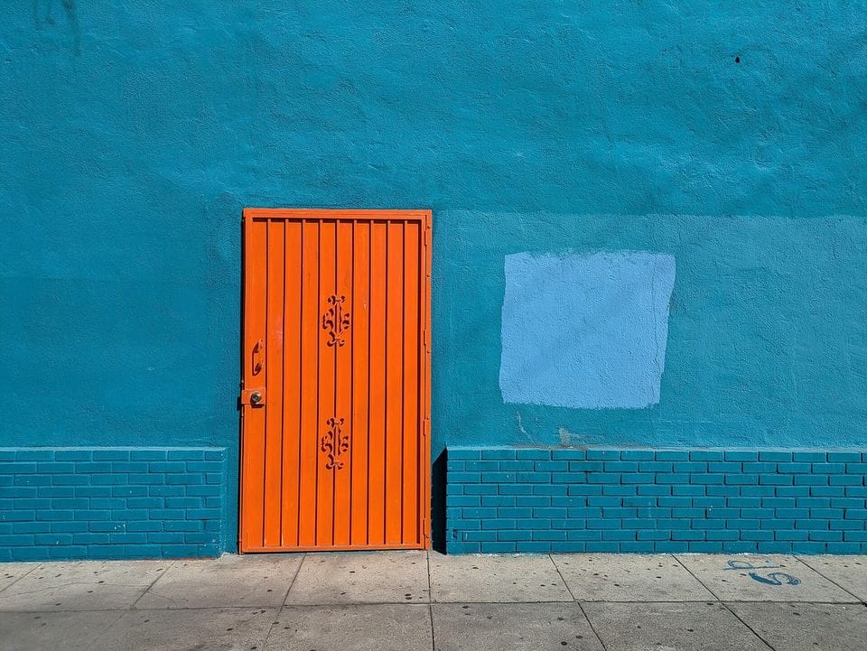 Orange door set in a teal painted wall