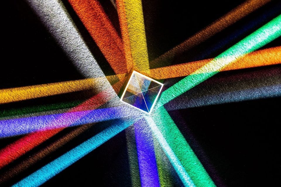Beams of coloured light splitting through a glass prism